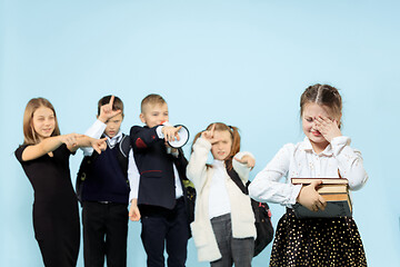 Image showing Little girl sitting alone on chair and suffering an act of bullying.