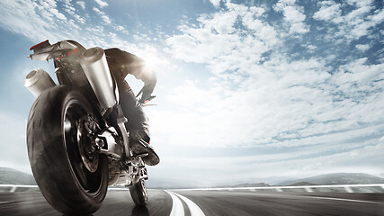 Image showing Biiker on highway, riding around a curve with a motion blur toned