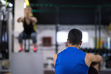 Image showing woman working out with personal trainer jumping on fit box