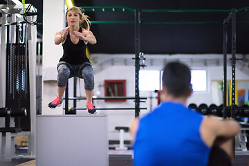 Image showing woman working out with personal trainer jumping on fit box