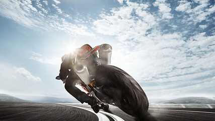 Image showing Biiker on highway, riding around a curve with a motion blur toned