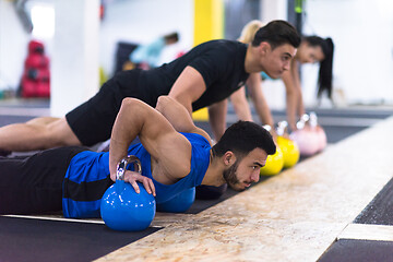 Image showing young athletes doing pushups with kettlebells