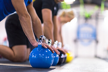 Image showing young athletes doing pushups with kettlebells