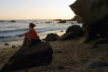 Image showing woman sitting along on rock at beach