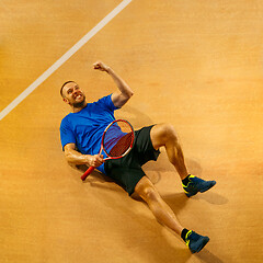 Image showing Portrait of a handsome male tennis player celebrating his success at court