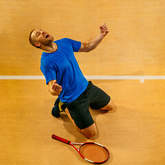 Image showing Portrait of a handsome male tennis player celebrating his success at court