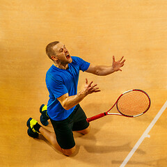 Image showing Portrait of a handsome male tennis player celebrating his success at court