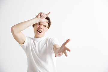 Image showing Losers go home. Portrait of happy guy showing loser sign over forehead