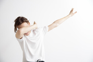 Image showing Young man makes the dab movement with his arms on a gray background.