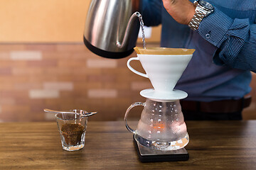 Image showing Barista pouring water on coffee with filter