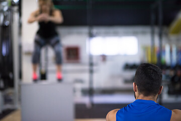 Image showing woman working out with personal trainer jumping on fit box