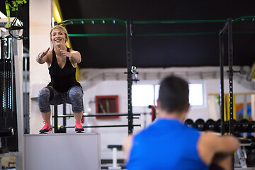 Image showing woman working out with personal trainer jumping on fit box