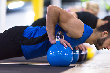 Image showing young athletes doing pushups with kettlebells