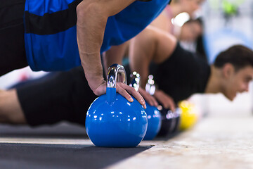 Image showing young athletes doing pushups with kettlebells