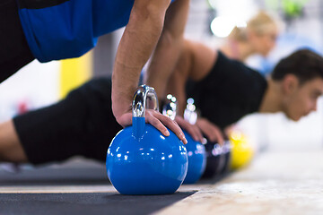 Image showing young athletes doing pushups with kettlebells