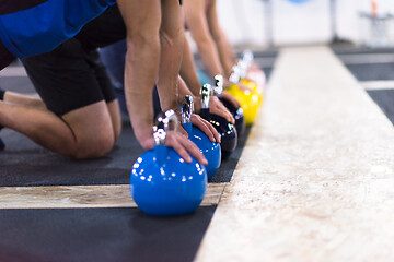 Image showing young athletes doing pushups with kettlebells