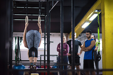 Image showing woman working out with personal trainer on gymnastic rings