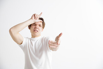 Image showing Losers go home. Portrait of happy guy showing loser sign over forehead