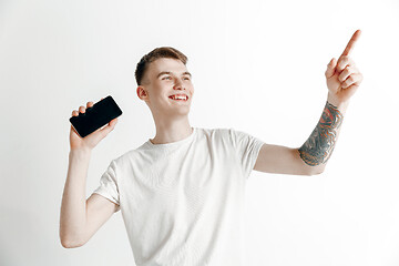 Image showing Young handsome man showing smartphone screen and signing OK isolated on gray background