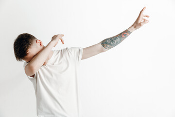 Image showing Young man makes the dab movement with his arms on a gray background.