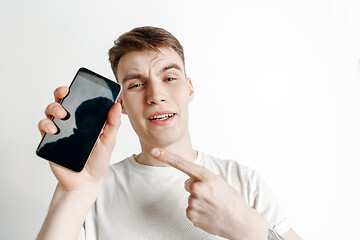 Image showing Young handsome man showing smartphone screen and signing OK isolated on gray background