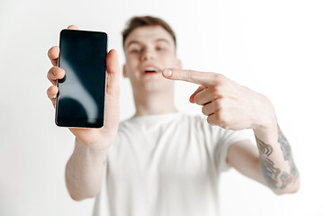 Image showing Young handsome man showing smartphone screen and signing OK isolated on gray background