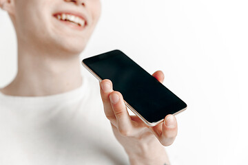 Image showing Indoor portrait of attractive young man holding smartphone