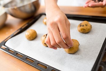 Image showing Woman putting dough on metal tray