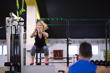 Image showing woman working out with personal trainer jumping on fit box