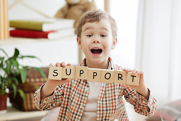 Image showing Wooden cubes with word SUPPORT in hands of little boy