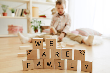 Image showing Wooden cubes with words WE ARE FAMILY in hands of little boy