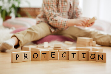 Image showing Wooden cubes with word PROTECTION in hands of little boy