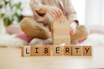 Image showing Wooden cubes with word LIBERTY in hands of little boy