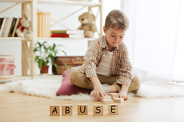 Image showing Wooden cubes with word ABUSE in hands of little boy