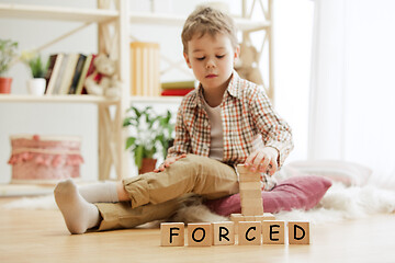 Image showing Wooden cubes with word FORCED in hands of little boy