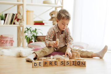 Image showing Wooden cubes with word DEPRESSION in hands of little boy