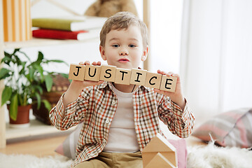 Image showing Wooden cubes with word justice in hands of little boy