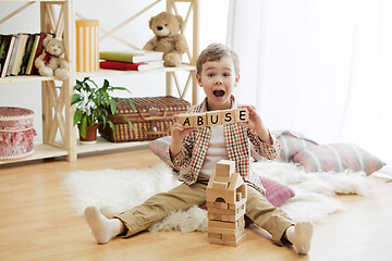 Image showing Wooden cubes with word ABUSE in hands of little boy