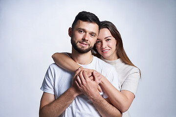 Image showing Smiling young couple hugging, studio portrait over light background