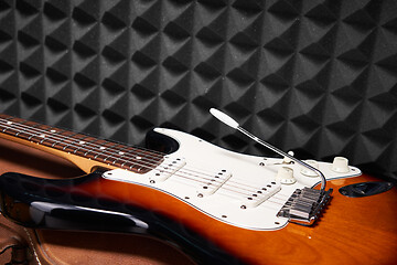 Image showing Sunburst electric guitar lying on acoustic foam panel background