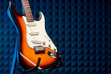 Image showing Sunburst electric guitar standing over acoustic foam panel background