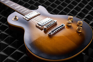 Image showing Sunburst electric guitar lying on acoustic foam panel background