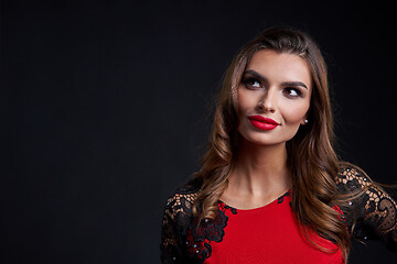 Image showing Closeup woman in red dress and red lips makeup looking away