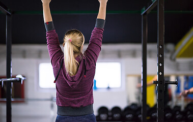 Image showing woman doing pull ups on the horizontal bar