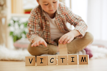 Image showing Wooden cubes with word VICTIM in hands of little boy