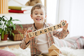 Image showing Wooden cubes with word LEARNING in hands of little boy