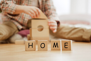 Image showing Wooden cubes with word HOME in hands of little boy