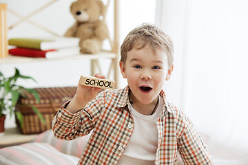 Image showing Wooden cubes with word SCHOOL in hands of little boy
