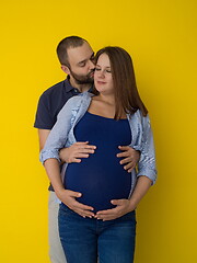 Image showing pregnant couple  isolated over yellow background