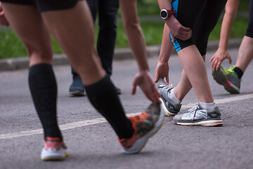 Image showing runners team warming up and stretching before morning training